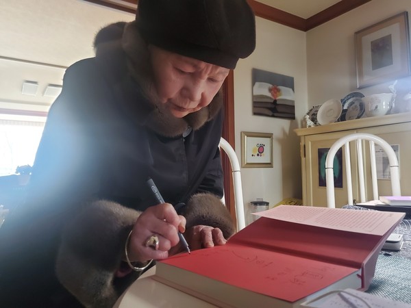 김현경 여사가 김수영 전집에 자필 사인을 하고 있다.