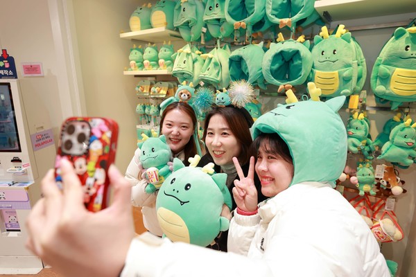 시민들이 에버랜드 기프트 샵에 진열된 용인특례시 공식 캐릭터 조아용과 에버랜드 인기 캐릭터 레시의 캐릭터 협력 상품을 착용하고 사진을 찍고 있는 모습. /사진=용인시